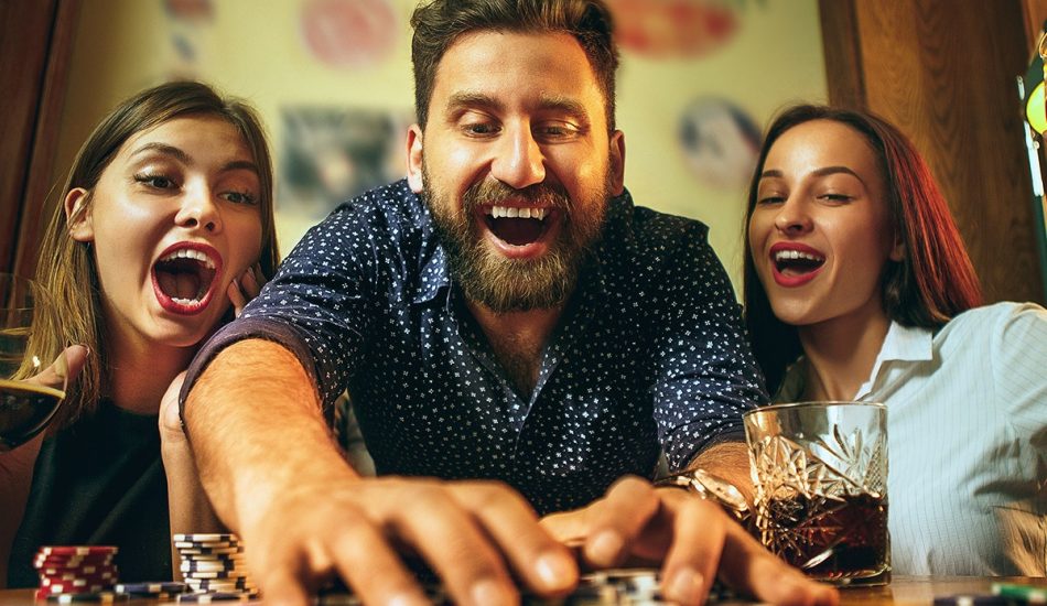 Close up of man holding smartphone and betting on the game while supporters celebrating the victory in background. Man using mobile in pub during football match. Soccer fans cheering for league in pub while man using smart phone to gamble with copy space.